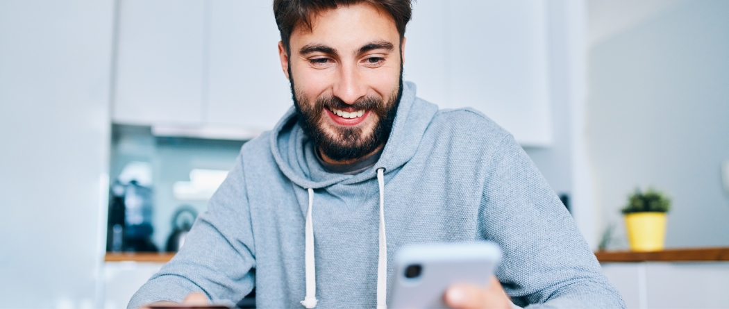 Man smiling and looking down at cell phone