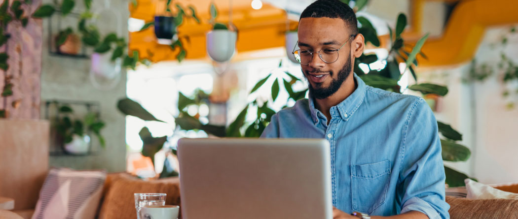 young man using a laptop in a room with lots of house plants
