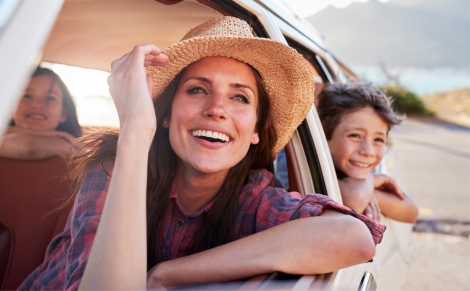 Woman and children leaning out car window and smiling