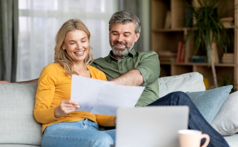 Couple smiling while reviewing papers on couch