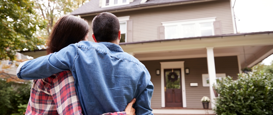 Couple hugging in front of new home